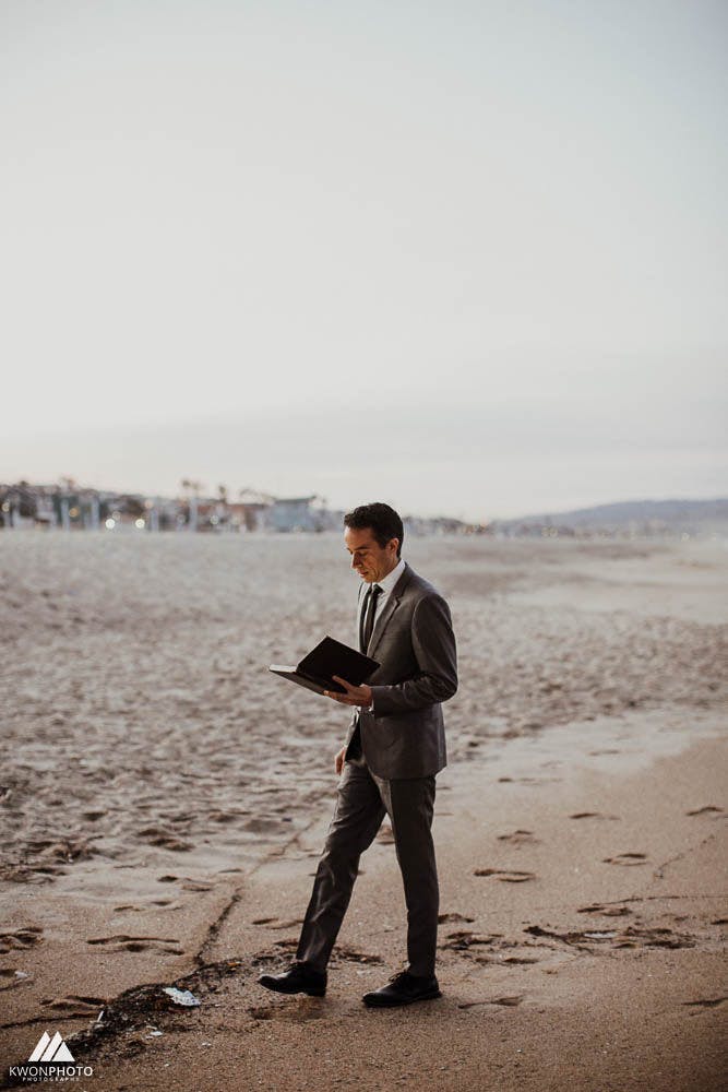 a photo of jacob looking at his officiant book as he walks on the beach