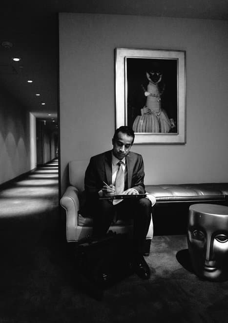 a black and white photo of Jacob sitting on a chair signing the license