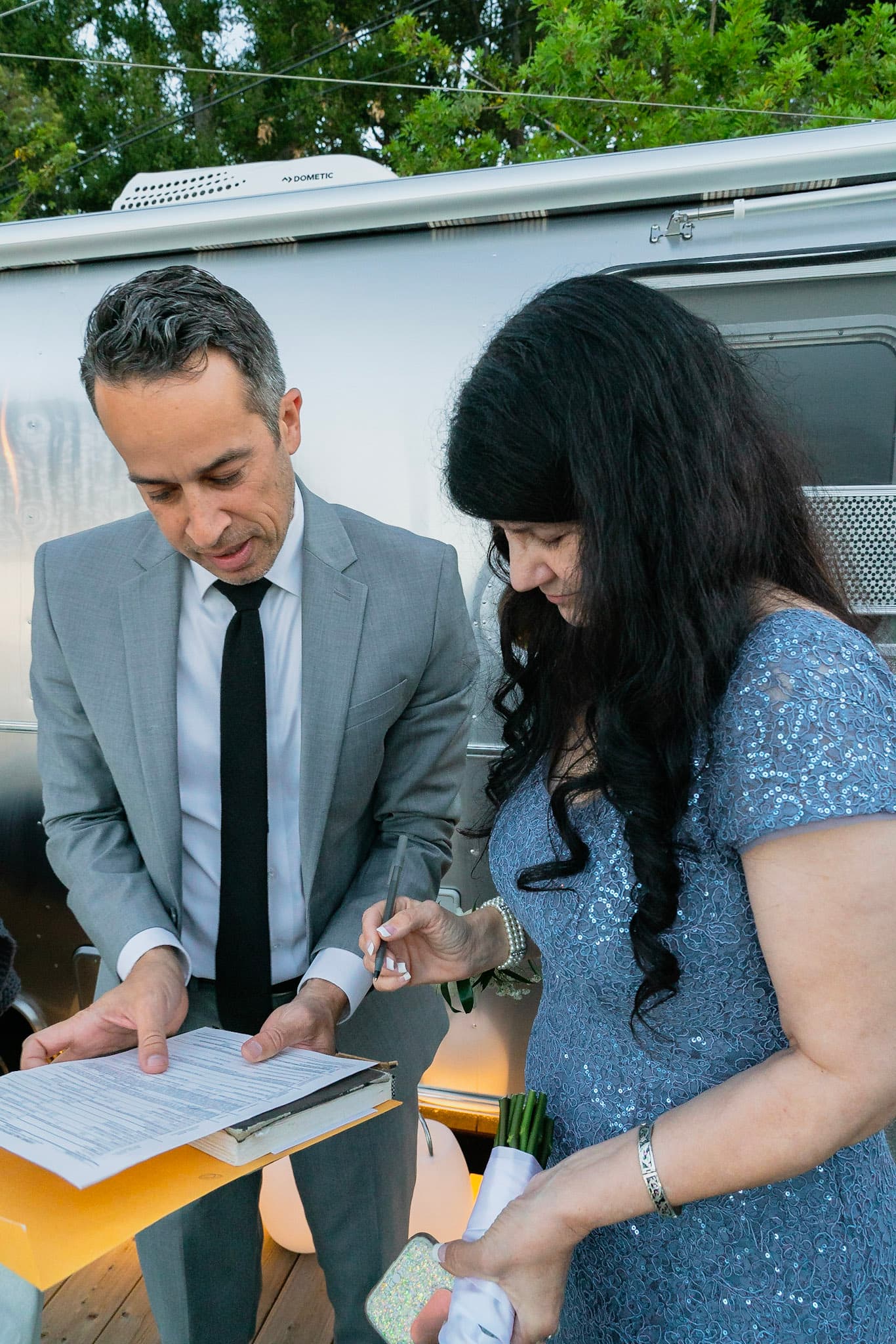 Jacob is instructing a woman where to sign on the marriage license